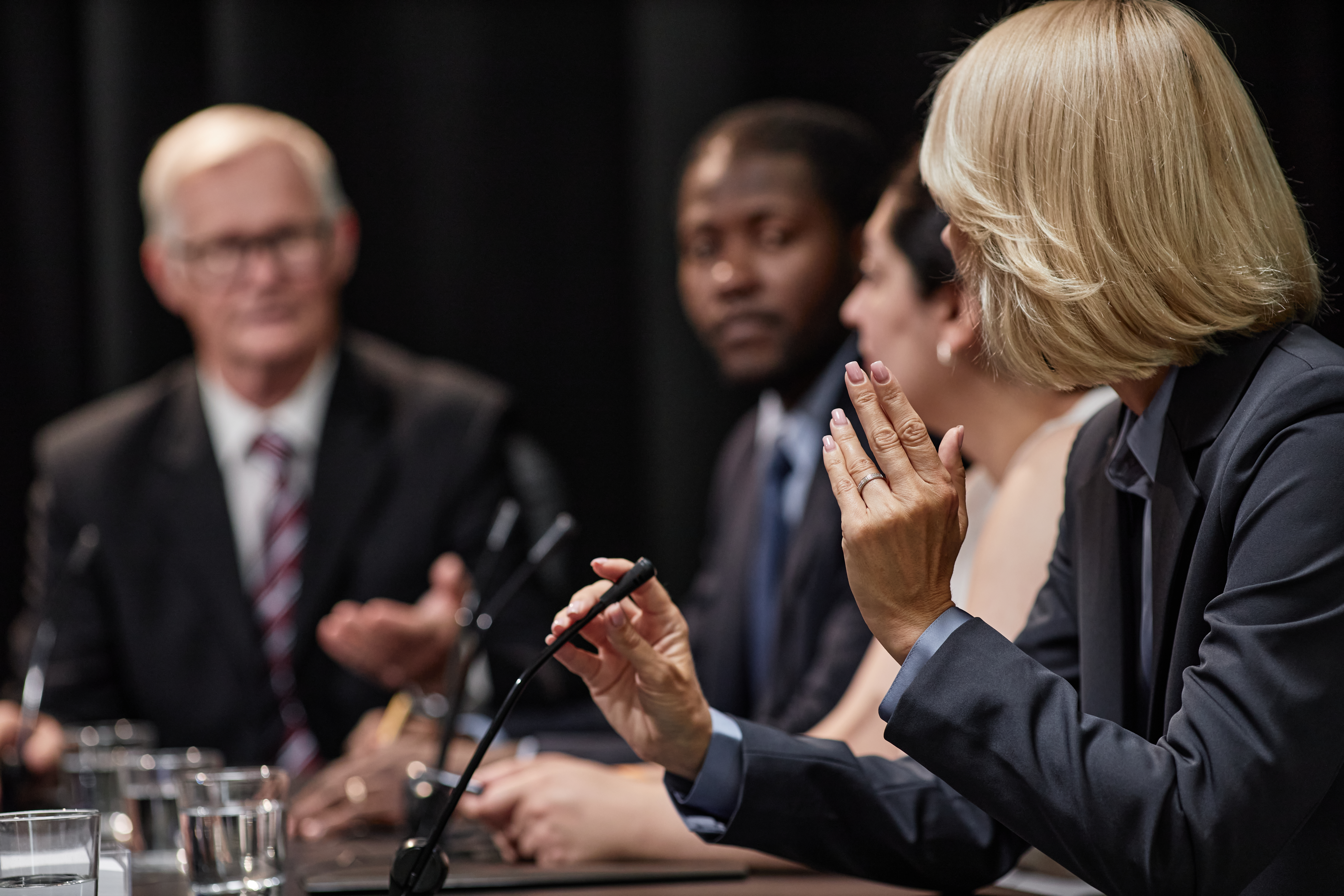 Woman asking a question of a speaker during a public panel discussion